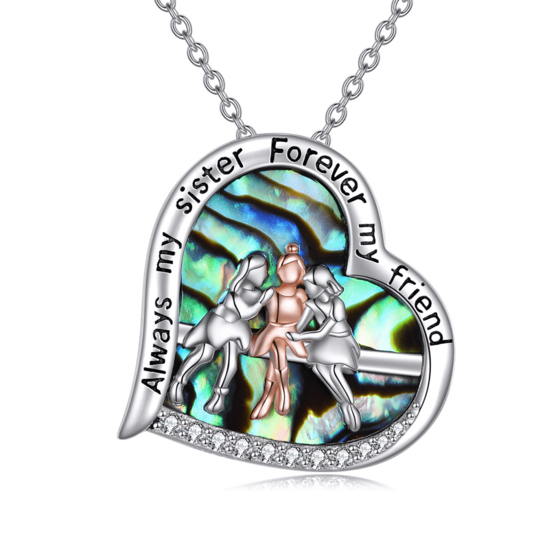 Heart-shaped silver pendant engraved with the words 'My Sister Forever My Friend' around the edge, featuring a colorful, iridescent background and dancing figures inside.