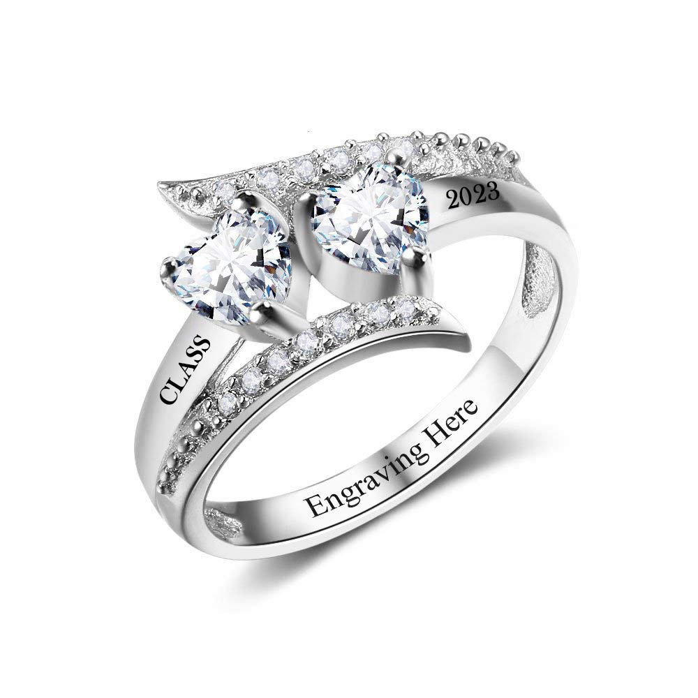 Engagement ring set with two heart-shaped diamonds and a pavé diamond band, inner engraving area visible.