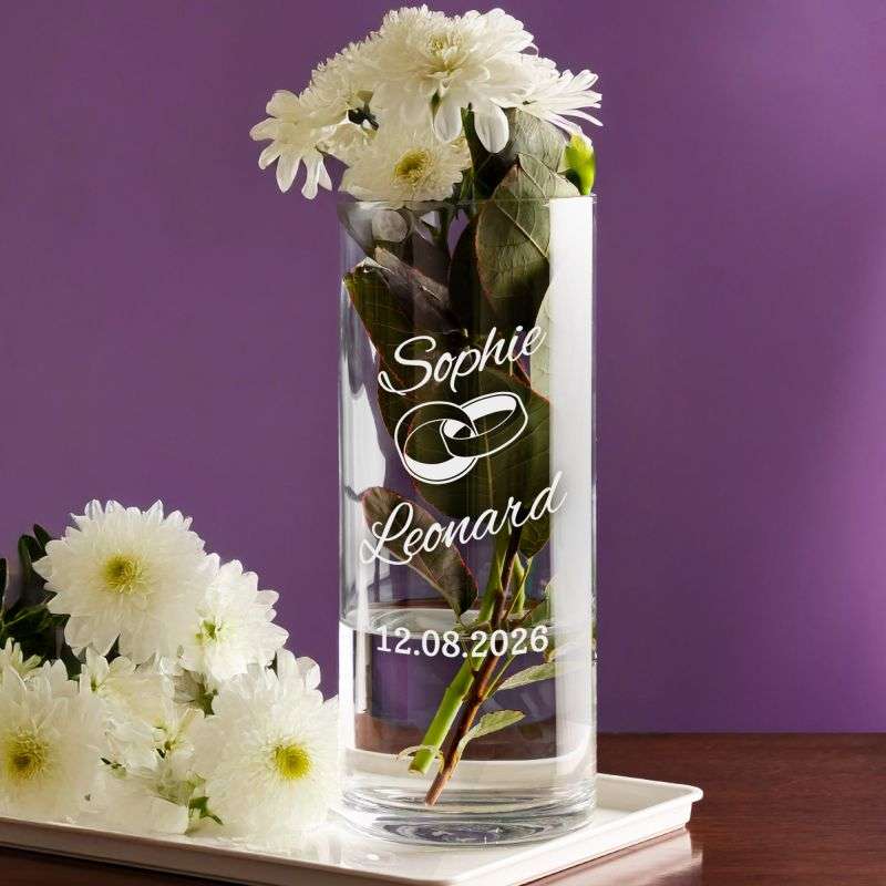 Glass vase with white chrysanthemums against a purple background, engraved with the names Sophie Leonard and the date 12.08.2026.